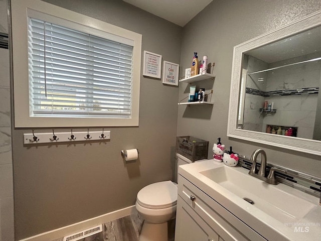 bathroom with vanity, toilet, hardwood / wood-style flooring, and a shower