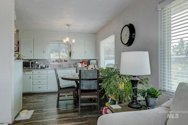 dining room with an inviting chandelier, sink, dark hardwood / wood-style flooring, and a healthy amount of sunlight