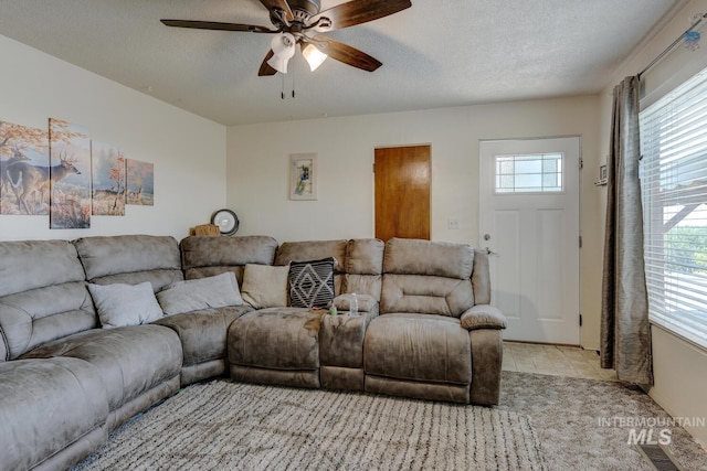 tiled living room with a textured ceiling and ceiling fan