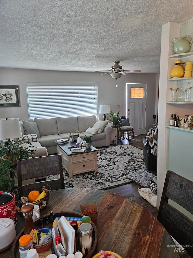 living room featuring hardwood / wood-style flooring, a textured ceiling, and ceiling fan