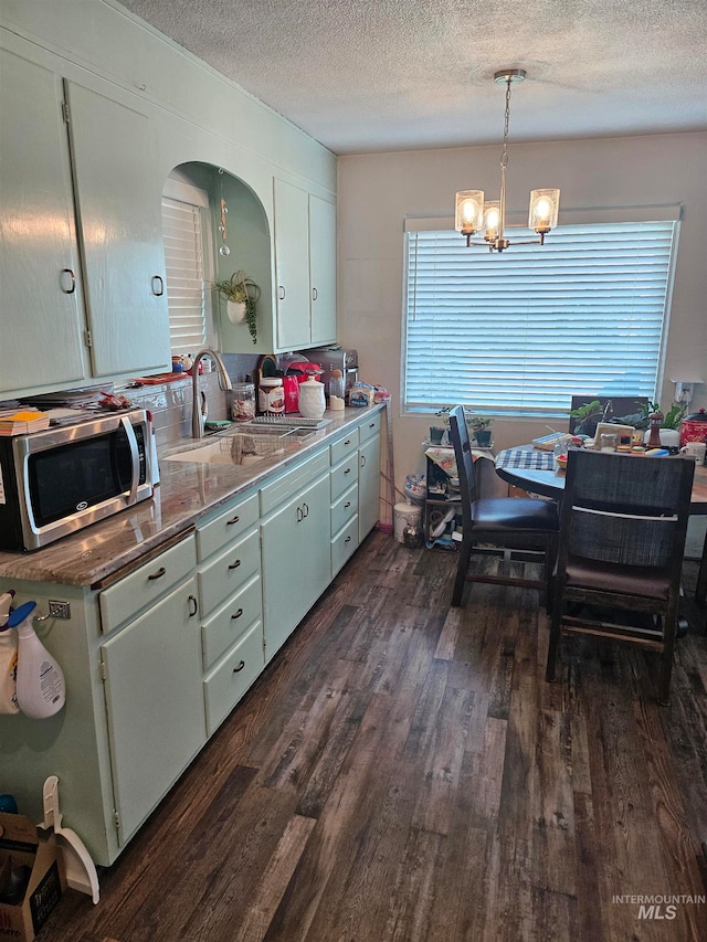 kitchen with sink, pendant lighting, dark hardwood / wood-style floors, a textured ceiling, and a notable chandelier