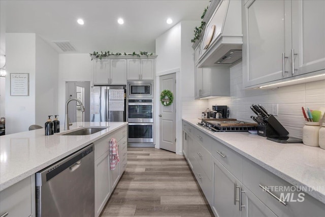 209 W 13th Ave, Jerome, ID 83338 - kitchen featuring appliances with stainless steel finishes, a sink, premium range hood, light wood-style floors, and tasteful backsplash