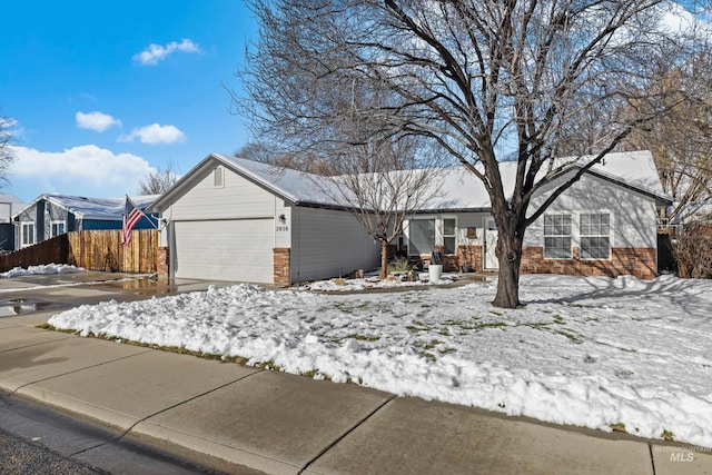 single story home with a garage, concrete driveway, brick siding, and fence