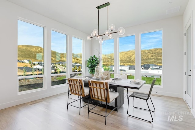 sunroom / solarium featuring a mountain view, an inviting chandelier, and plenty of natural light