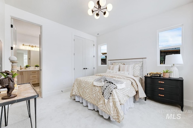 carpeted bedroom with connected bathroom, multiple windows, and a chandelier