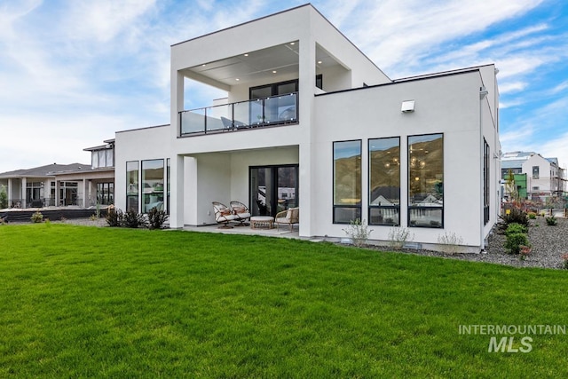 rear view of house with a patio area, a lawn, and a balcony