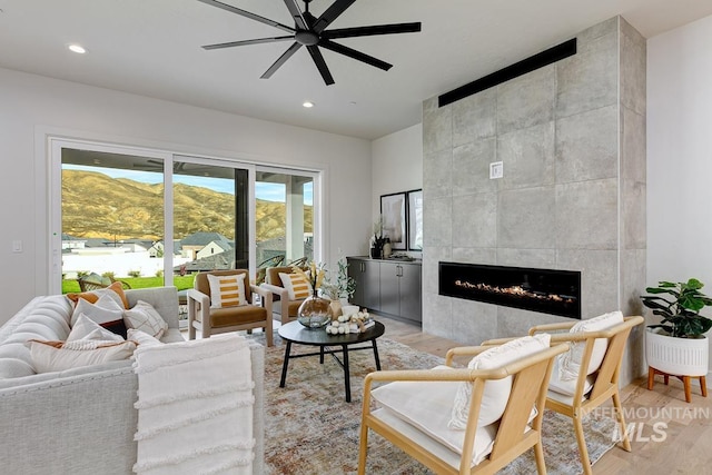 living room with light hardwood / wood-style flooring, a mountain view, a fireplace, and ceiling fan