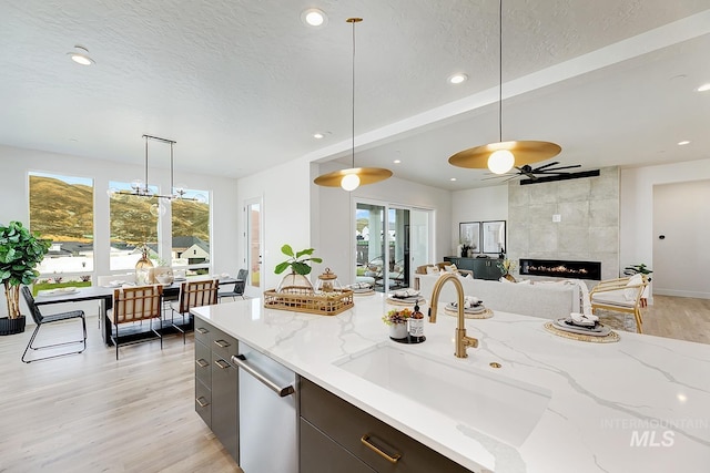 kitchen with light stone countertops, a wealth of natural light, a tile fireplace, and pendant lighting