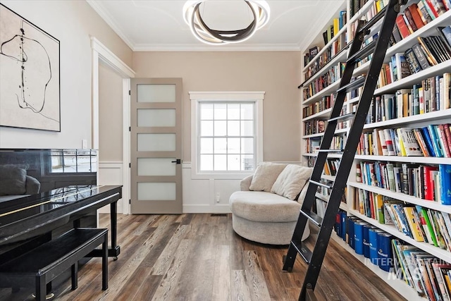 living area with a wainscoted wall, ornamental molding, dark wood finished floors, and bookshelves