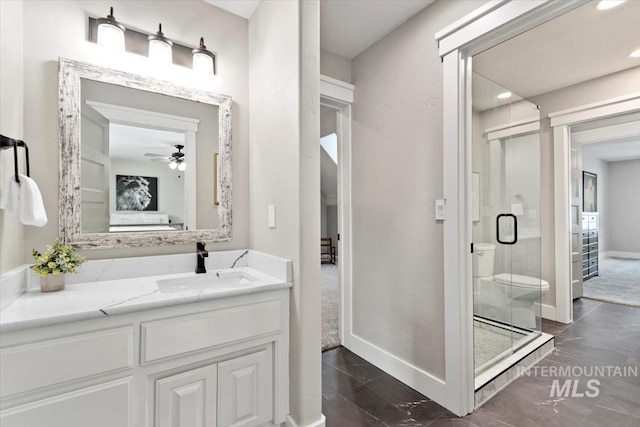 ensuite bathroom featuring baseboards, connected bathroom, toilet, vanity, and a shower stall