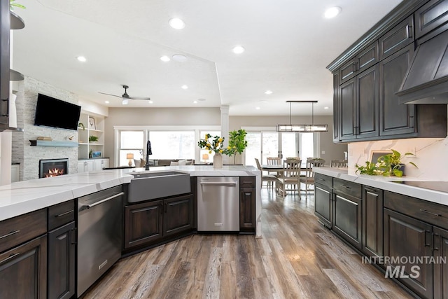 kitchen featuring custom range hood, a sink, hanging light fixtures, and stainless steel dishwasher