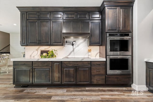 kitchen featuring stainless steel double oven, light countertops, dark brown cabinetry, and black electric cooktop