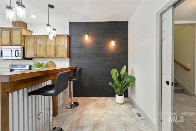 kitchen with stove, pendant lighting, and a kitchen bar