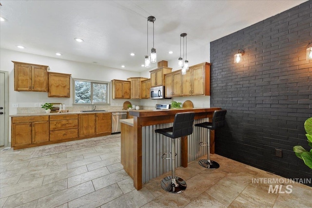 kitchen with sink, a kitchen bar, stainless steel appliances, brick wall, and decorative light fixtures