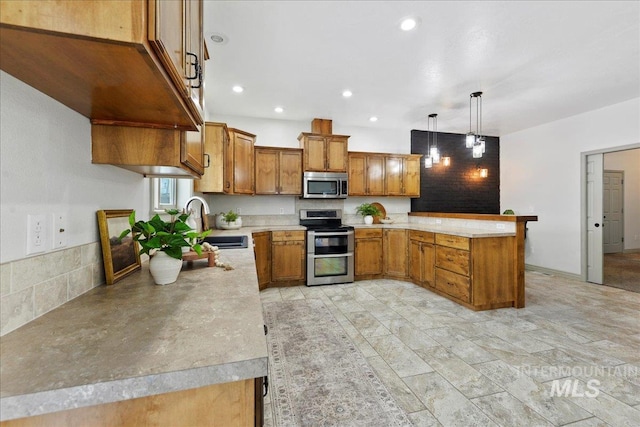 kitchen featuring appliances with stainless steel finishes, sink, kitchen peninsula, and decorative light fixtures