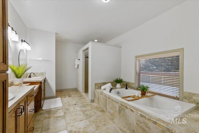 bathroom featuring a relaxing tiled tub and vanity