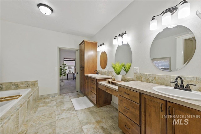 bathroom featuring a relaxing tiled tub and vanity