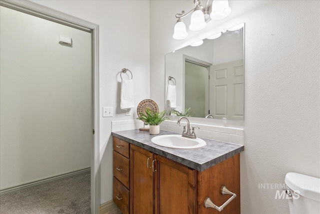 bathroom with vanity, a notable chandelier, and toilet