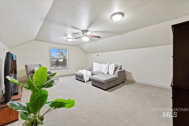 interior space featuring ceiling fan, vaulted ceiling, light carpet, and a textured ceiling