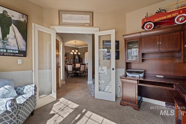 home office with arched walkways, wainscoting, french doors, and an inviting chandelier