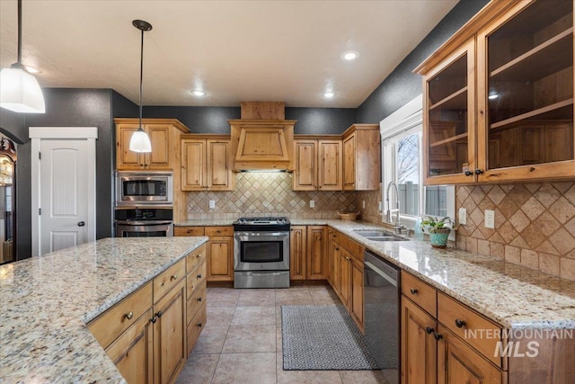 kitchen with a sink, light stone counters, custom exhaust hood, and appliances with stainless steel finishes