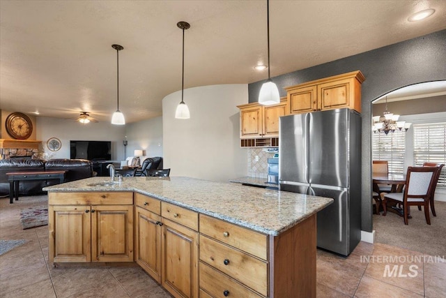 kitchen featuring light stone counters, backsplash, a sink, and freestanding refrigerator