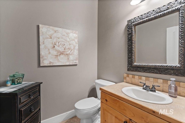 half bathroom featuring decorative backsplash, baseboards, toilet, and vanity