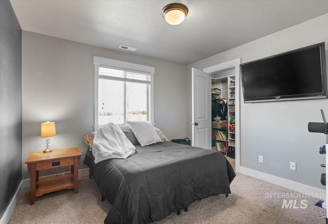 bedroom featuring a spacious closet, visible vents, baseboards, carpet, and a closet