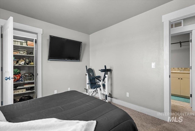 carpeted bedroom with a sink, visible vents, and baseboards