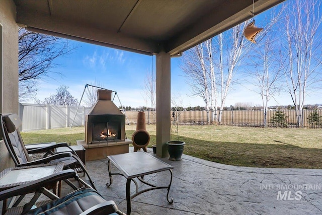 view of patio / terrace with a warm lit fireplace and a fenced backyard