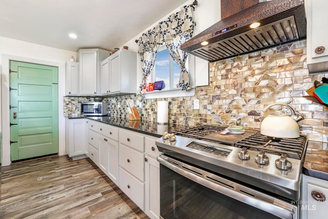 kitchen with white cabinets, backsplash, wall chimney exhaust hood, and stainless steel appliances