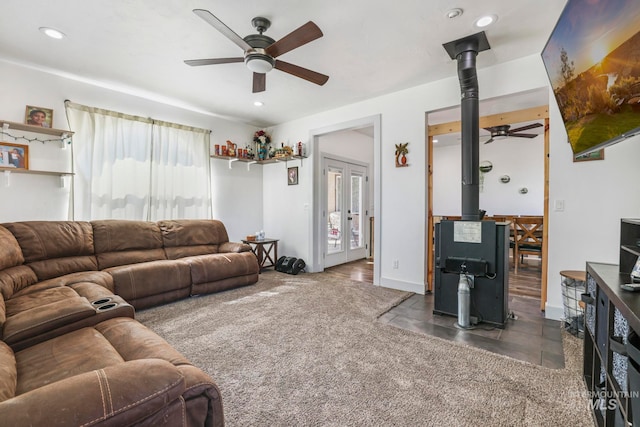 living room featuring ceiling fan, a wood stove, and french doors