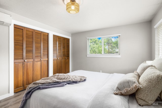 473 E Ranch Dr, Eagle, ID 83616 - bedroom featuring wood finished floors, two closets, an AC wall unit, and baseboards