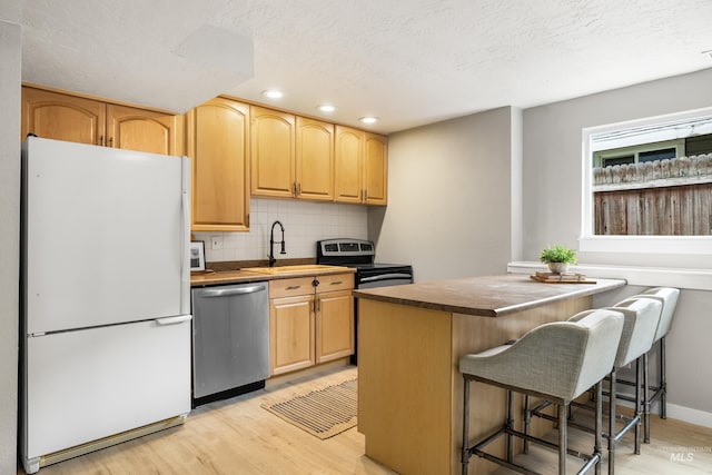 473 E Ranch Dr, Eagle, ID 83616 - kitchen with stainless steel appliances, a sink, light wood finished floors, tasteful backsplash, and a kitchen bar