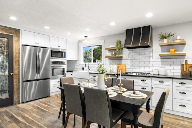 473 E Ranch Dr, Eagle, ID 83616 - kitchen featuring appliances with stainless steel finishes, open shelves, range hood, a sink, and dark countertops