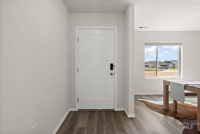 foyer entrance with dark wood-style flooring, visible vents, and baseboards