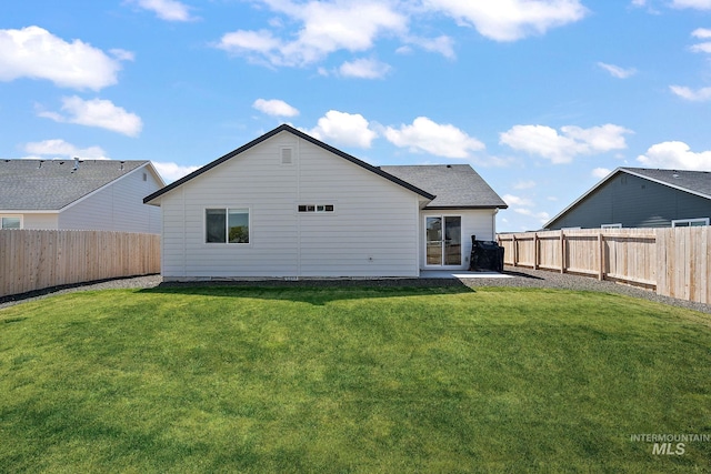 rear view of property with roof with shingles, a yard, and a fenced backyard