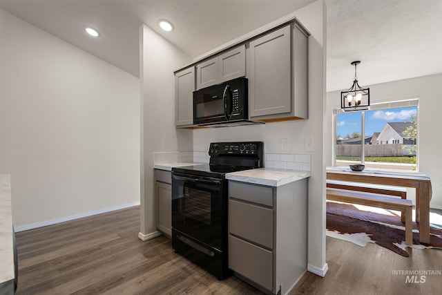 kitchen with dark wood-style floors, gray cabinets, black appliances, and an inviting chandelier