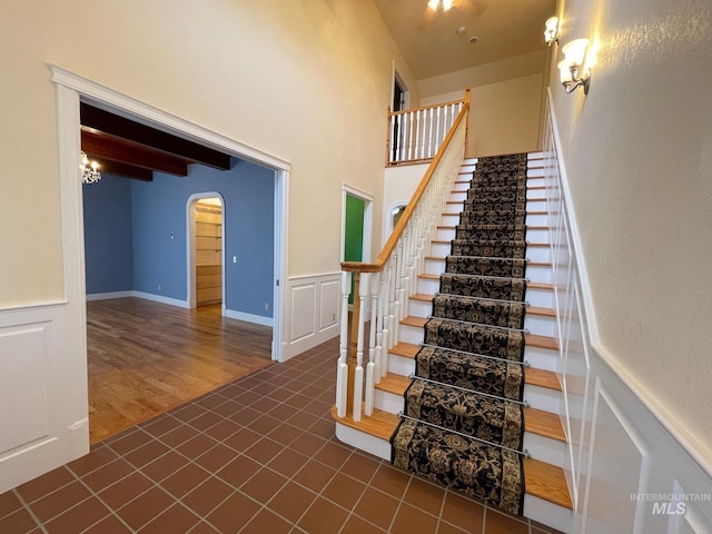 stairway featuring beam ceiling and tile patterned floors