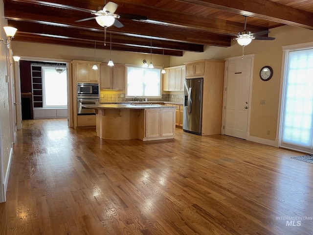 kitchen featuring appliances with stainless steel finishes, tasteful backsplash, a kitchen island, pendant lighting, and beam ceiling