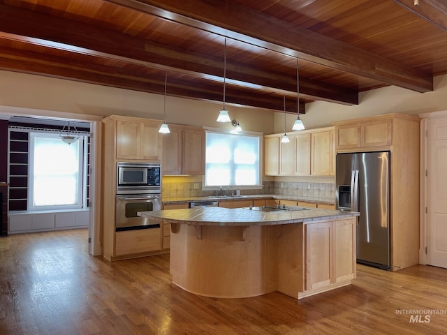 kitchen featuring tile countertops, a kitchen island, plenty of natural light, and appliances with stainless steel finishes