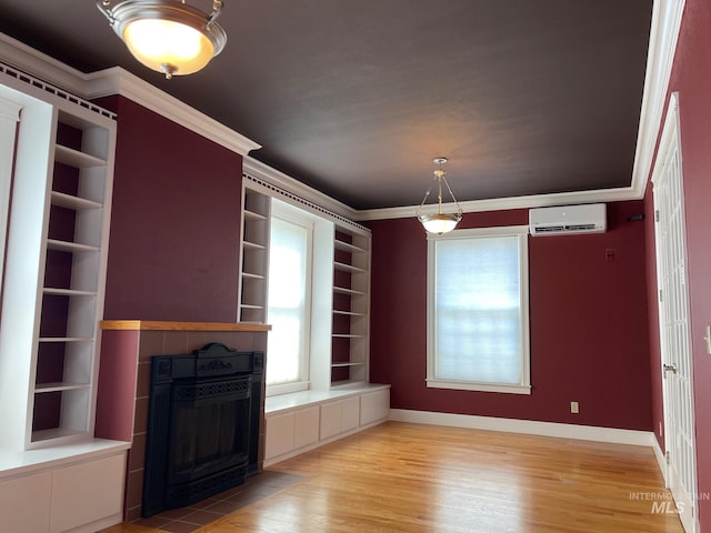 unfurnished dining area featuring a tile fireplace, ornamental molding, light hardwood / wood-style flooring, a wall mounted AC, and built in shelves