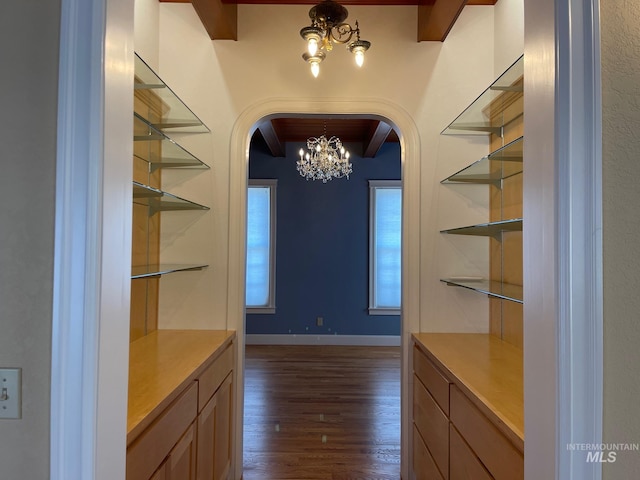 interior space featuring dark wood-type flooring, an inviting chandelier, and beamed ceiling