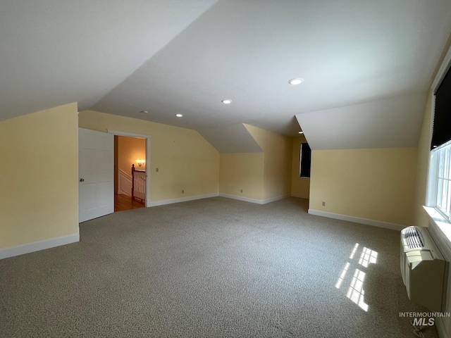 additional living space featuring vaulted ceiling, carpet, and a wall mounted air conditioner