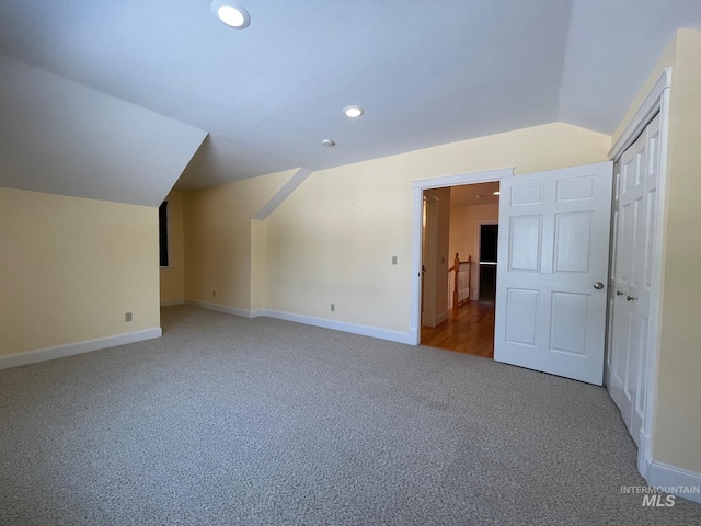 additional living space featuring vaulted ceiling and carpet