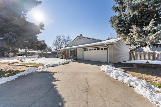 ranch-style home with concrete driveway, fence, and an attached garage