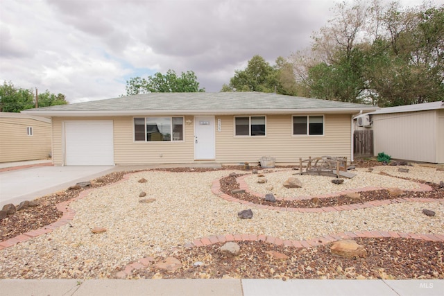 ranch-style home featuring an attached garage, concrete driveway, and a wall mounted AC