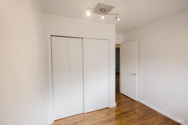 unfurnished bedroom featuring a closet, light wood finished floors, baseboards, and ceiling fan