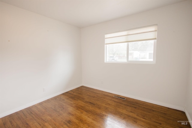 spare room featuring wood finished floors and baseboards