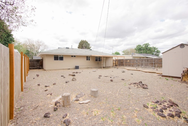 back of house with a fenced backyard, a storage shed, and an outbuilding